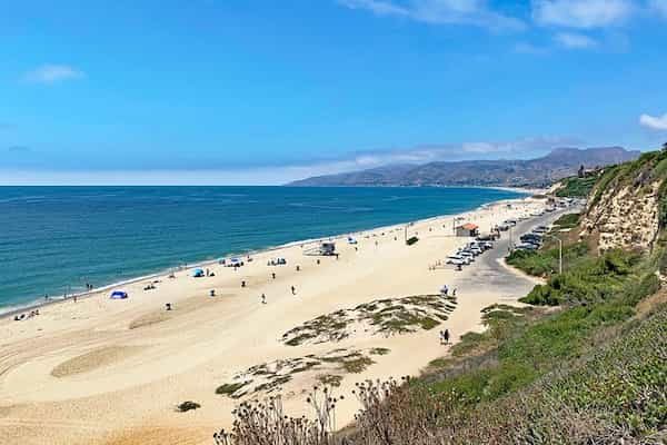 Extiende una toalla en la playa de Zuma